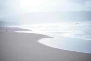 die Schaumwelle am Sandstrand. sanfte Wellen an der Küste, die sich ruhig und angenehm zum Entspannen anfühlen. foto