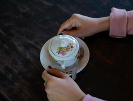 Auf dem Tisch steht eine Tasse heißen Kaffee. Ein Mädchen hält ein leckeres Getränk in der Hand. eine Art Freizeitvergnügen. foto