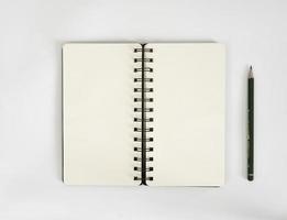 weißer Schreibtisch mit Skizzenbuch und Bleistift darauf. ein Notebook-Modell auf dem Schreibtisch als Arbeitsplatzlayout. Büroobjekt isoliert auf weißem Hintergrund. foto