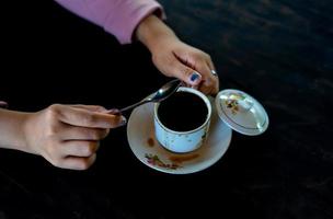 Auf dem Tisch steht eine Tasse heißen Kaffee. Ein Mädchen hält ein leckeres Getränk in der Hand. eine Art Freizeitvergnügen.