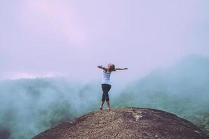 asiatische frauen reisen im urlaub entspannen. stehende Hände auf einer felsigen Klippe. wildes naturholz auf dem berg. foto