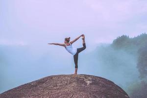asiatische frauen entspannen sich im urlaub. spielen, wenn Yoga. auf der Bergfelsenklippe foto