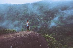 asiatische frauen reisen im urlaub entspannen. stehende Hände auf einer felsigen Klippe. wildes naturholz auf dem berg. foto