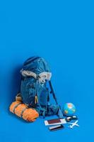 das Konzept der Organisation von Reiseausrüstung im Gepäck. Konzeptzubehör für Reisende Urlaub mit Karte, Reisepass auf blauem Hintergrund. Reiserucksack foto