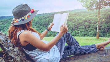 asiatische frauen entspannen sich im urlaub. auf der Bank im Park ein Buch lesen. foto