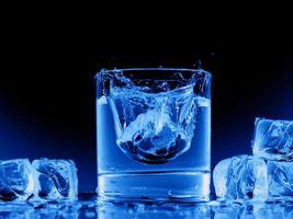 blaues Wasser transparente Flasche Glasspritzer abstrakt mit Blasen auf Schwarz.
