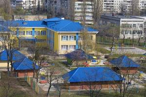 hellblaues Dach des Kindergartens vor dem Hintergrund grauer städtischer Hochhäuser foto