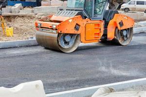 große Vibrationswalzen arbeiten auf einer Baustelle und verdichten frischen Asphalt. foto