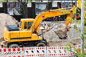 Schwerer Straßenbagger gräbt einen Graben auf einer Baustelle. foto