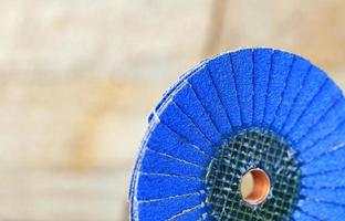 Lamellenschleifscheibe blau auf Holz und Metall auf hellbeigem Grund in unscharf. foto