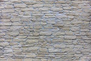 Textur einer beigen Steinmauer einer großen Kopfsteinpflasternahaufnahme foto