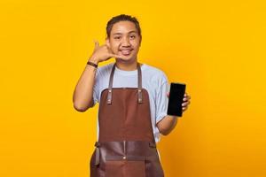 Porträt eines fröhlichen asiatischen jungen Mannes, der Smartphone hält und Telefongeste mit den Händen macht foto