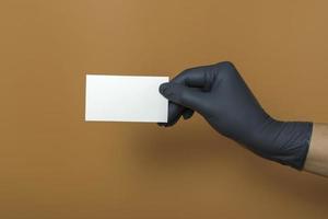 weißes Visitenkartenmodell auf farbigem Hintergrund. eine Hand in einem medizinischen Handschuh hält eine Visitenkarte foto
