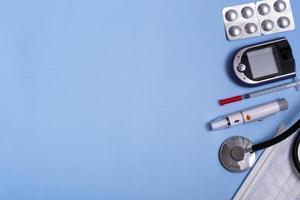 medizinisches Konzept auf blauem Hintergrund Stethoskop, Lanzettenstift, Blutzuckermessgerät, Maske und Pillen. Nahaufnahme Kopie Raum Diabetes Konzept. foto
