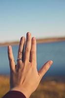 Symbol der Liebe, das prominent auf der Hand der jungen Frau angezeigt wird. Schatten auf der Handseite. Fluss- und Herbstgräser im Hintergrund. sonniger blauer Himmel im Horizont vorhanden. foto