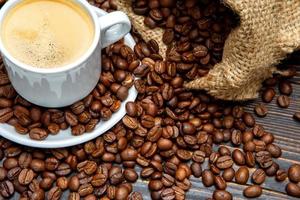 Tasse Kaffee und Bohnen auf Holzuntergrund foto