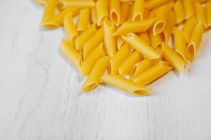 Pasta Penne Rigate auf einem weißen Holztisch Hintergrund foto