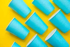 Muster aus blauen Einwegbechern aus Papier auf gelbem Grund foto