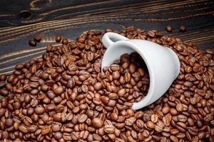 geröstete Kaffeebohnen und Tasse auf Holzuntergrund