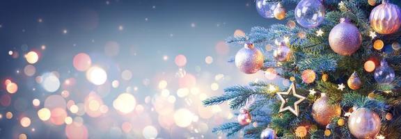 Weihnachtsbaum mit goldenen Kugeln und glänzenden Lichtern auf blauem Hintergrund foto