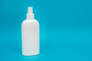 weiße Plastikflasche zum Sprühen von flüssiger Kosmetik auf blauem Hintergrund foto