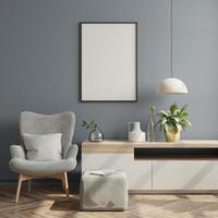 Postermodell mit vertikalen Rahmen an leerer dunkler Wand im Wohnzimmer mit samtgrauem Sessel.
