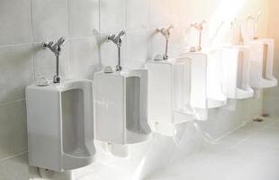 Reihe von Urinaltoiletten für den Mann an der gefliesten Wand in der öffentlichen Toilette foto