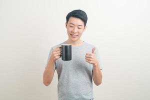 junger asiatischer mann, der kaffeetasse hält foto