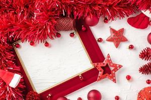 Weihnachtsroter Bilderrahmen und Christbaumkugeldekorationsverzierung auf weißem Betontischhintergrund foto