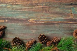 Weihnachtskiefertanne mit Tannenzapfendekoration auf rustikalem Holztischhintergrund der Weinlese