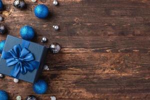 Weihnachtsblaue Geschenkbox und Silberkugeldekorationsverzierung auf Holztischhintergrund foto