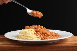 Food-Stylist verwendet Löffel, um italienisches Essen zu dekorieren foto