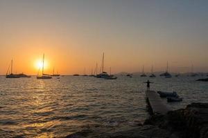 Männer am Pier im Sonnenuntergang am Strand von Ses illietes auf der Insel Formentera im Sommer 2021 foto