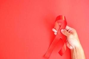 Die rote Schleife ist ein internationales Zeichen für HIV und trägt zur Sensibilisierung bei. Personen, die rote Schleifen tragen, um ihre Unterstützung für diejenigen zu zeigen, die mit der Krankheit leben foto