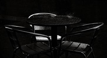 Tisch und Stühle in einem Café im Freien während des Regens foto