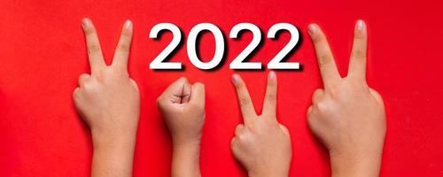 Idee und Kreativität im Jahr 2022, Fingerhandsymbol der Neujahrszahl auf rotem Hintergrund