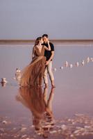 Mädchen und ein Mann am Ufer eines rosa Salzsees foto