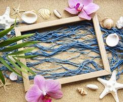 blaues Fischernetz und Holzrahmen auf einem Strandsand, Reisekonzept foto