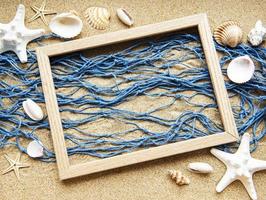 blaues Fischernetz und Holzrahmen auf einem Strandsand, Reisekonzept foto
