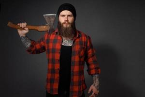 gut aussehender Mann mit langen Haaren mit einer Axt in den Händen auf dunklem Studiohintergrund foto