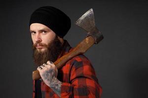 gut aussehender Mann mit langen Haaren mit einer Axt in den Händen auf dunklem Studiohintergrund foto