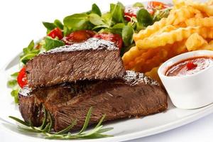 gegrilltes Steak, Pommes Frites und Gemüse auf weißem Hintergrund foto