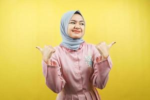 fröhliche schöne junge muslimische Frau, mit der Hand, die auf den leeren Raum zeigt, etwas fördert, isoliert foto