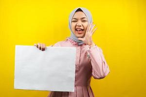hübsche junge muslimische Frau, die fröhliche leere leere Banner, Plakate, weiße Tafeln, leere Schilder, weiße Werbetafeln hält, etwas im Kopierraum präsentiert, Werbung