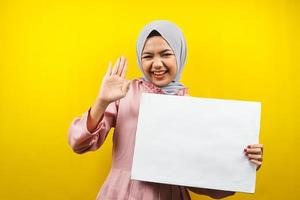 hübsche junge muslimische Frau, die fröhliche leere leere Banner, Plakate, weiße Tafeln, leere Schilder, weiße Werbetafeln hält, etwas im Kopierraum präsentiert, Werbung foto