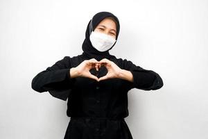 muslimische Frau mit weißer Maske, mit Händen, Zeichen der Liebe, Zuneigung, glücklich, isoliert auf weißem Hintergrund foto