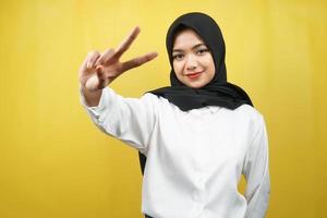 schöne junge asiatische muslimische frau schmollend mit v-signierten händen, ok, gute arbeit, vereinbarung, sieg, blick in die kamera einzeln auf gelbem hintergrund
