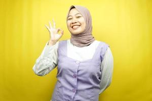 schöne junge asiatische muslimische frau, die selbstbewusst, enthusiastisch und fröhlich lächelt, mit händen ok zeichen, erfolg, gute arbeit, erfolgszeichen, isoliert auf gelbem hintergrund foto