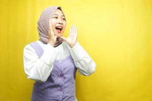 schöne junge asiatische muslimische frau schockiert, ungläubig, überrascht, einen leeren raum betrachtend, der etwas auf gelbem hintergrund isoliert präsentiert foto