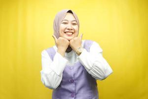 schöne junge asiatische muslimische frau, die glücklich lächelt, süß, sich wohl fühlt, sich umsorgt fühlt, sich gut fühlt, mit den händen, die das kinn einzeln auf gelbem hintergrund halten foto